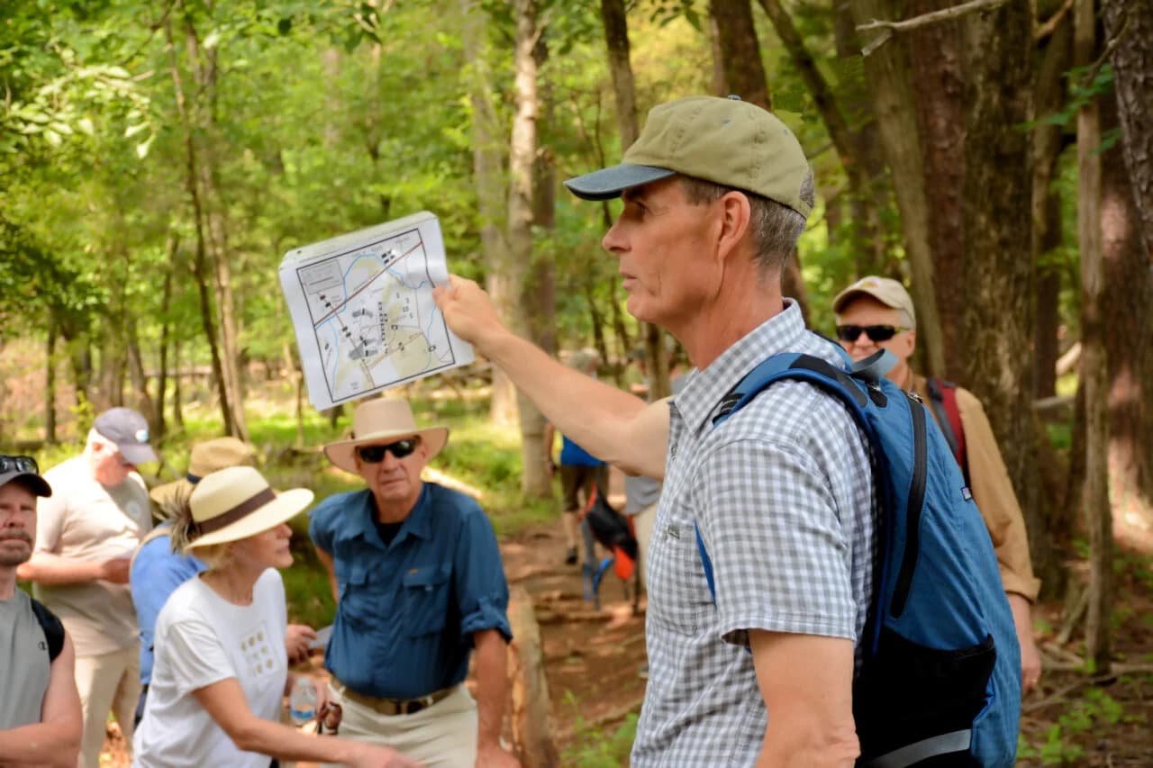 A guide leading visitors on a walking tour of the battlefield with a trail map